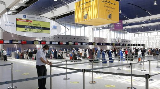 An airport employee wears a mask over his face organizes passenger queues and ensures strict compliance with the social distancing instructions seen above on a giant screen during the the COVID-19 pandemic at Mohammed V International Airport in Casablanca, Morocco, Wednesday July 15, 2020. Morocco has started to gradually reopen its air border after the borders were closed following the COVID-19 pandemic. Only Moroccan citizens and expatriates residing in Morocco will be allowed to travel in the first stage of the reopening. (AP Photo/Abdeljalil Bounhar)/JAL119/20197670335460//2007152206